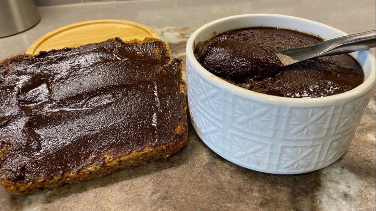 Pâte à tartiner aux noix de Grenoble & caroube Pâte à tartiner maison aux noix de Grenoble et caroube dans un petit pot en verre, avec texture crémeuse et couleur chocolatée.