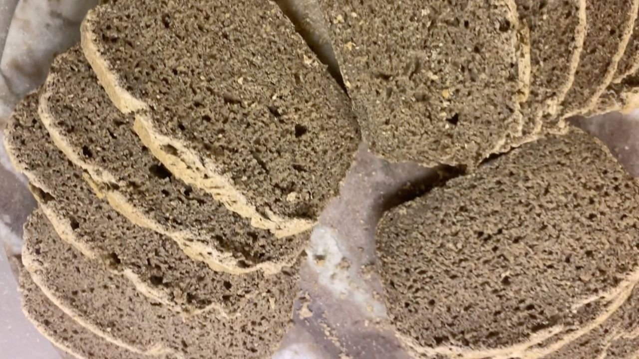 Pain au sarrasin au levain, rustique et moelleux, posé sur une planche en bois, avec une mie dense et légèrement humide.