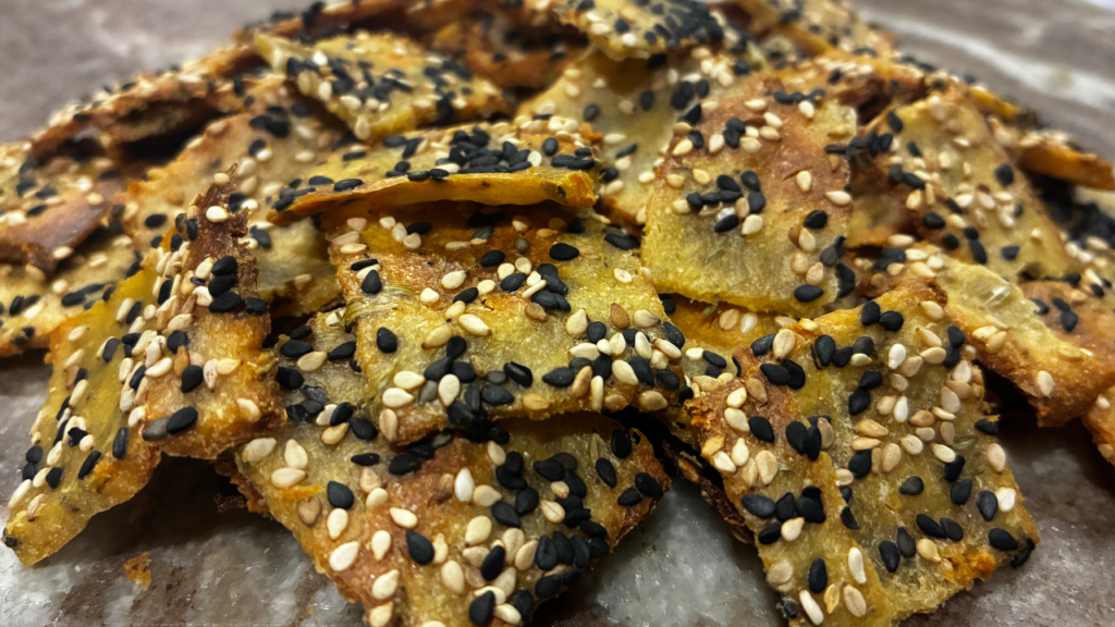 Craquelins de quinoa trempé, dorés et croustillants, étalés sur une plaque.