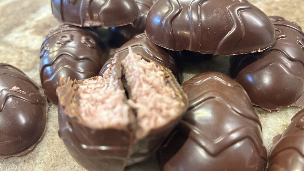 Bouchées de chocolat Bounty keto faites maison, avec garniture coco‑fraise fondante et enrobage de chocolat noir brillant.