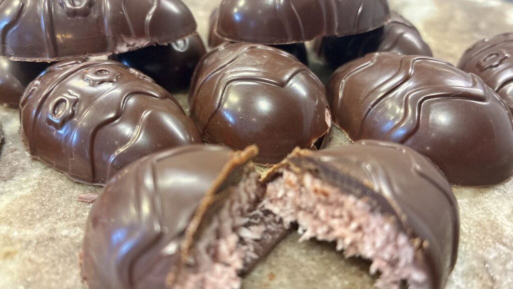 Bouchées de chocolat Bounty keto faites maison, avec garniture coco‑fraise fondante et enrobage de chocolat noir brillant.